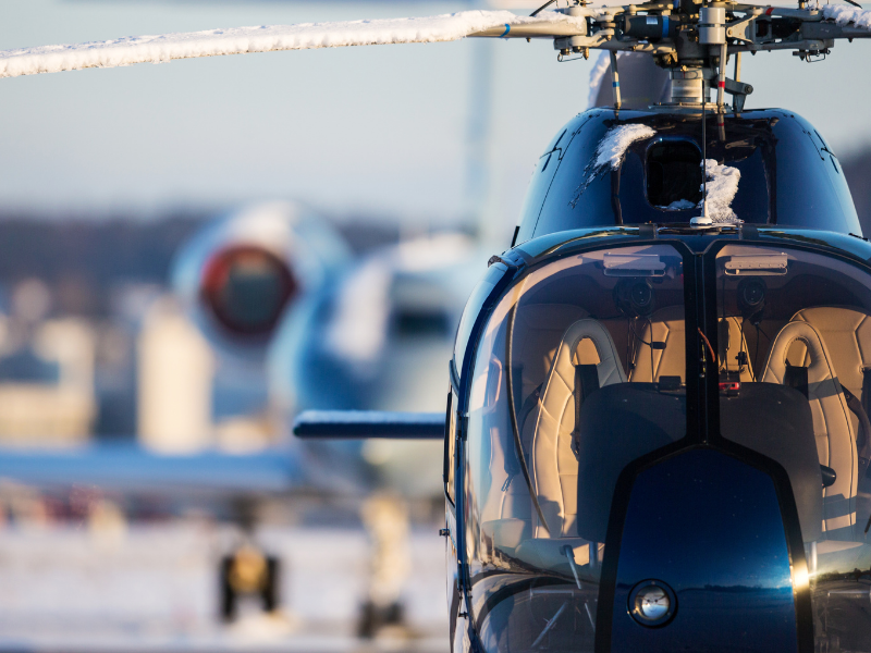Helicopter parked at an airfield with snow covered blades
