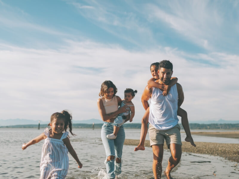 Family of five running and laughing together on the beach